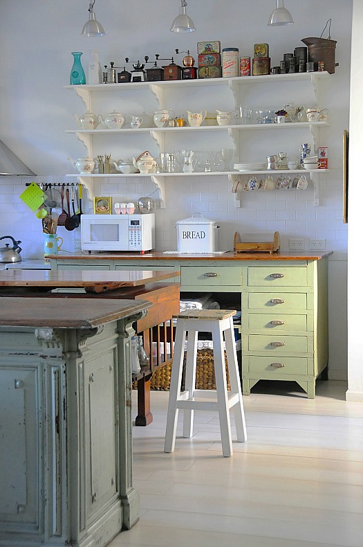 A kitchen with open shelving and pale green cabinets