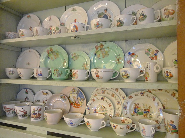 close up of china plates and teacups on display in cabinet