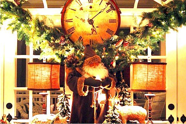 A clock in the middle of a living room with a christmas tree