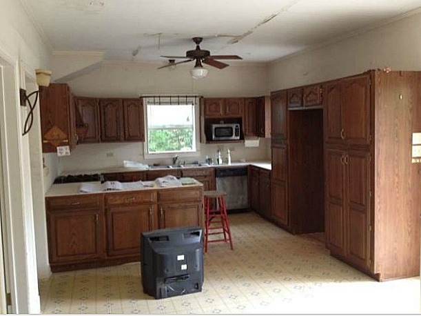 A kitchen with wooden cabinets in a room before remodel