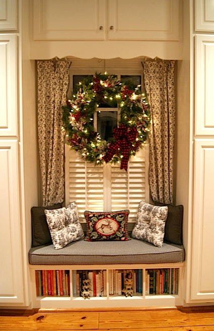 window seat with wreath hanging on window above it