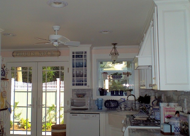 A kitchen with white cabinets and ceiling fan