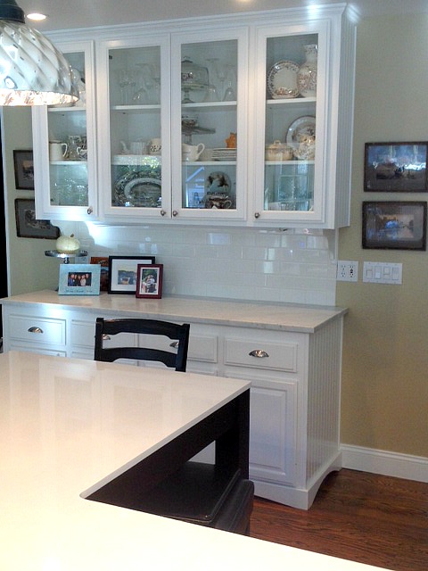A kitchen with glass doors on cabinets for display