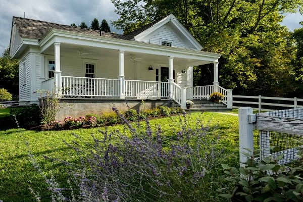 A garden in front of a small house with big front porch