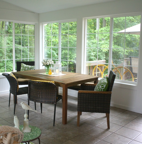 A dining room table in front of a window in sunroom