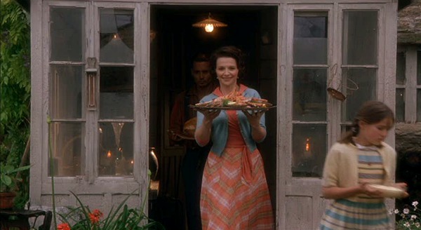 Juliette Binoche carrying a tray of food out into the yard