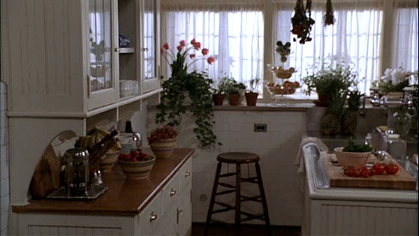 A room filled with furniture and vase of flowers on a kitchen counter