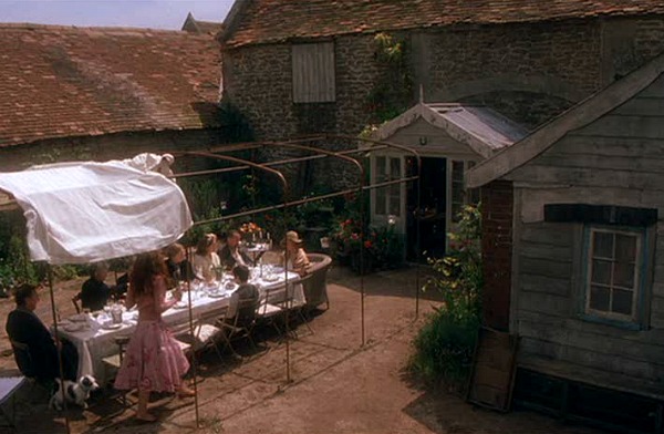 A group of people eating dinner at long table behind house