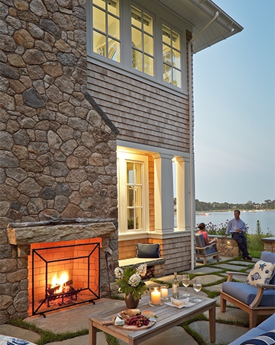 large stone outdoor fireplace on side of house