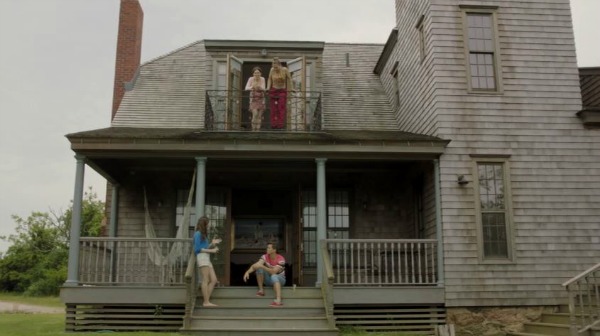 characters on porch and second floor balcony of shingle style house