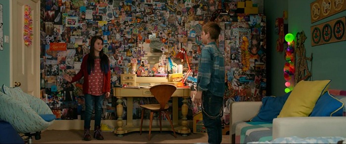 two characters stand in room covered in collage of images