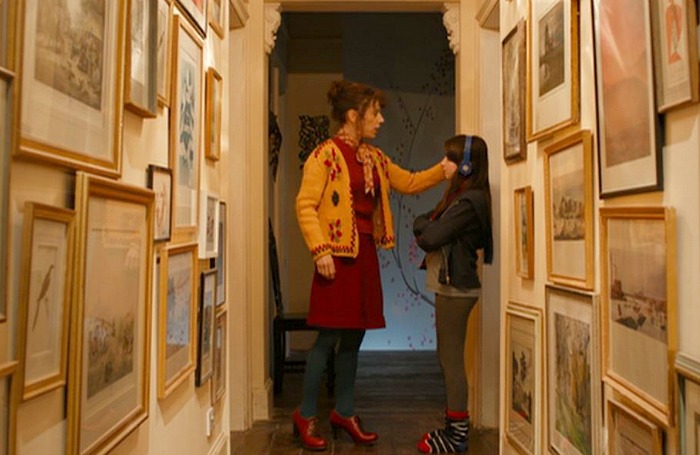 mother and daughter stand in upstairs hallways lined with framed artwork