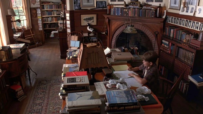 boy works at a desk next to a fireplace