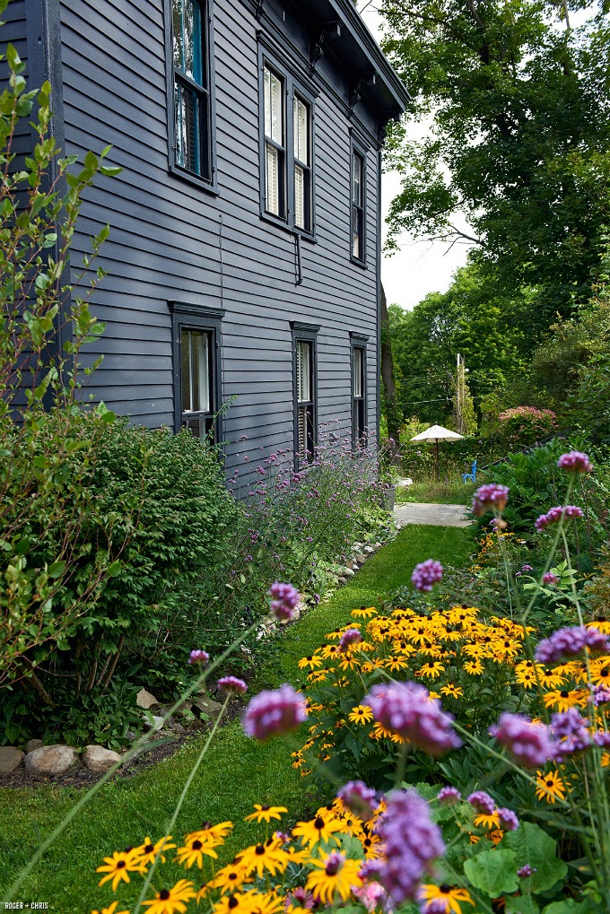 side of black house with cottage garden