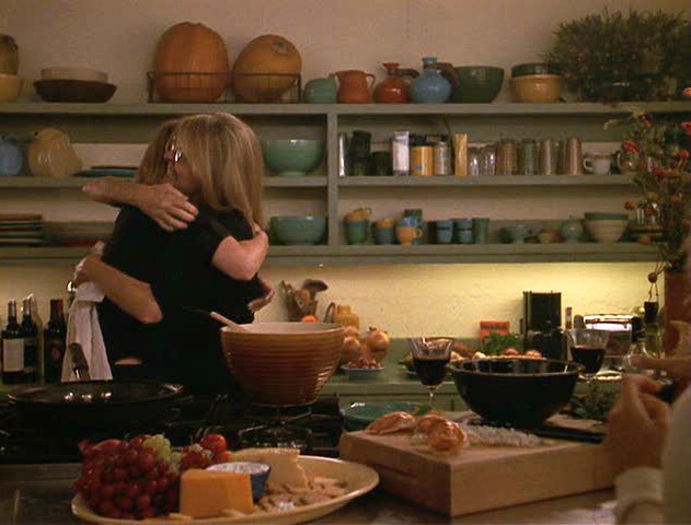 women hugging in kitchen with open shelving