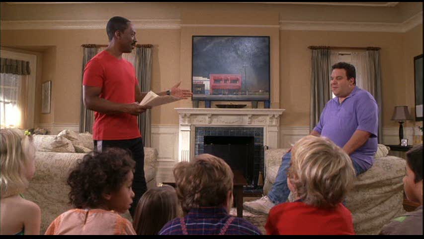 Eddie Murphy standing next to fireplace in living room