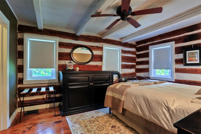 A bedroom with ceiling fan in log cabin