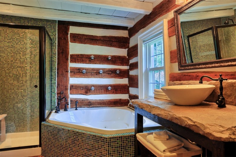 deep bathtub in corner of bathroom with log walls