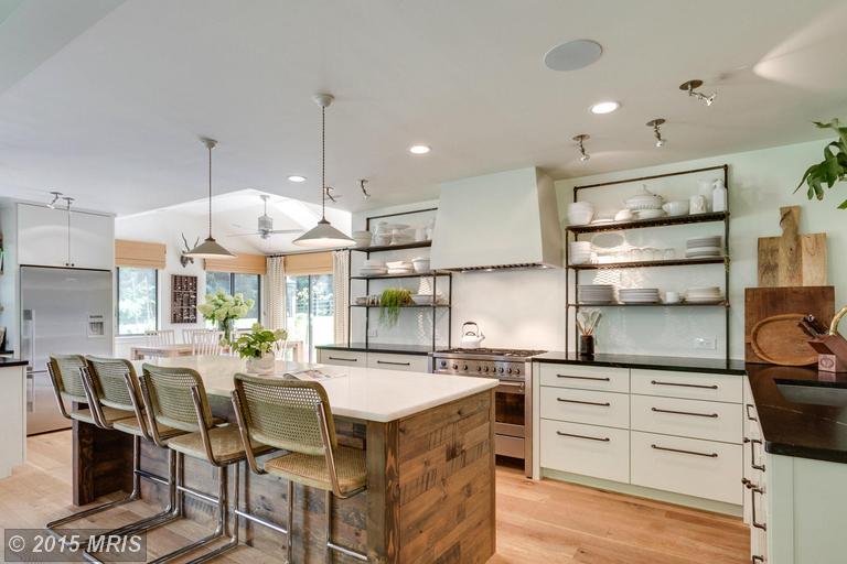 A kitchen with island and large vent hood over range