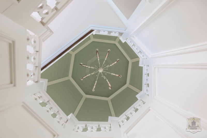 looking up staircase to chandelier at the top of the house