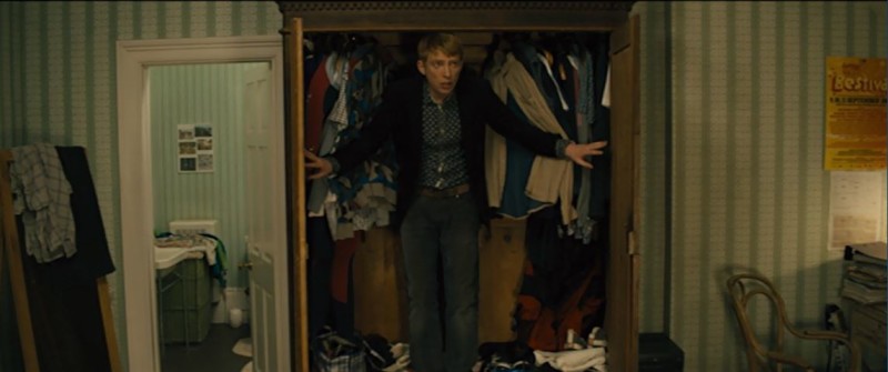 Character standing in wardrobe filled with clothes