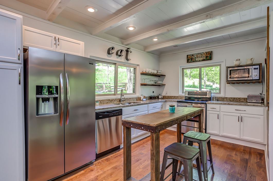 white kitchen with stainless refrigerator and sign that says EAT on wall