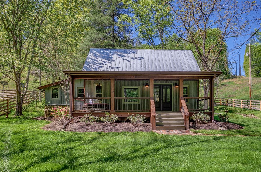 front exterior view of cabin in woods with front porch