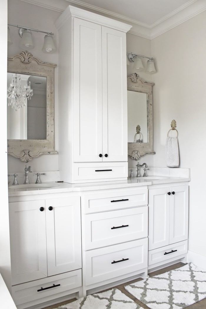 bathroom with two vanities and white cabinets