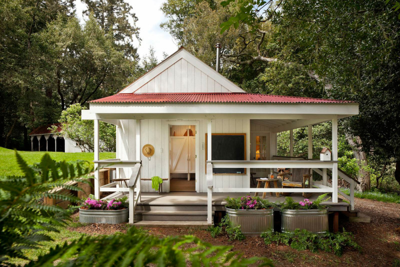 A little summer cottage painted white with red roof and front porch