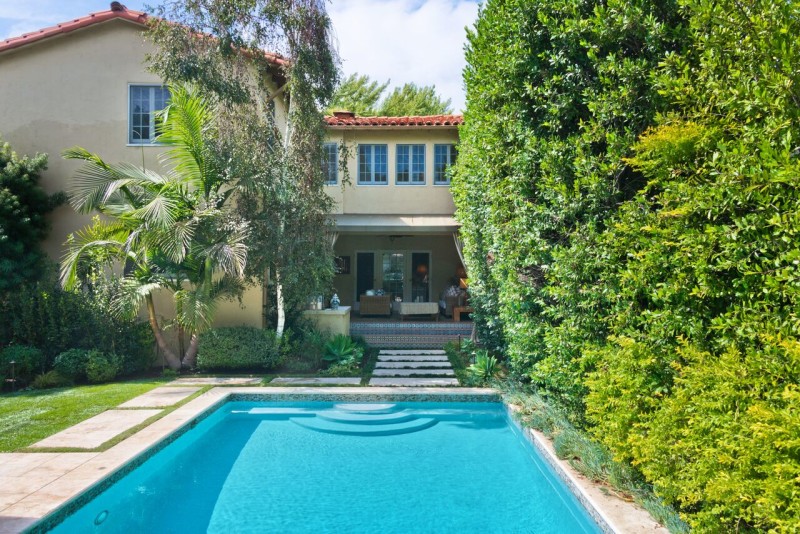 back exterior of Spanish style home with pool