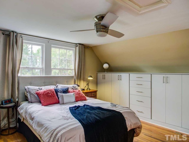 Upstairs bedroom with slanted dormer walls and built in storage