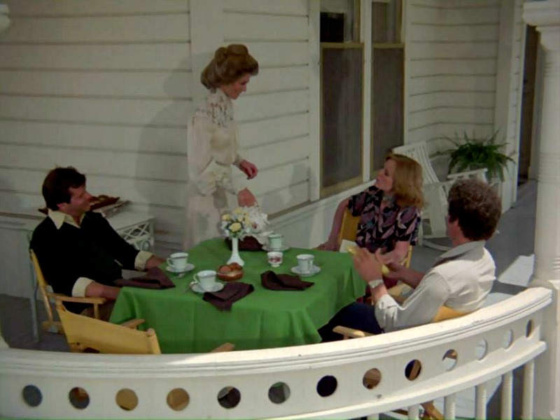 Group of people sitting around a table on the front porch