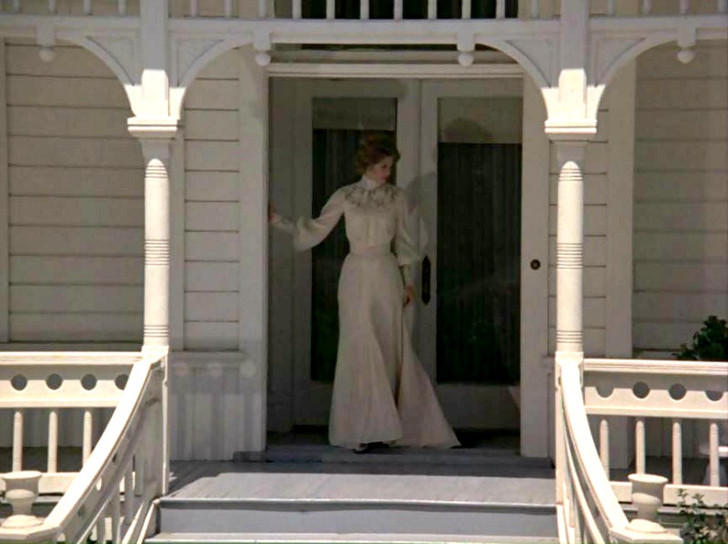 Jennie Logan steps out onto the front porch in the Victorian dress