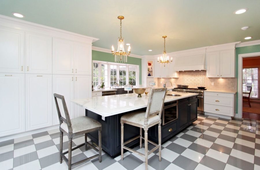 White kitchen with green wall, black island, marble countertops