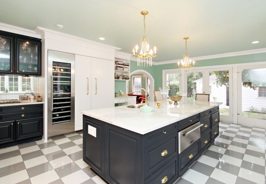 Large black island in kitchen with checkerboard flooring