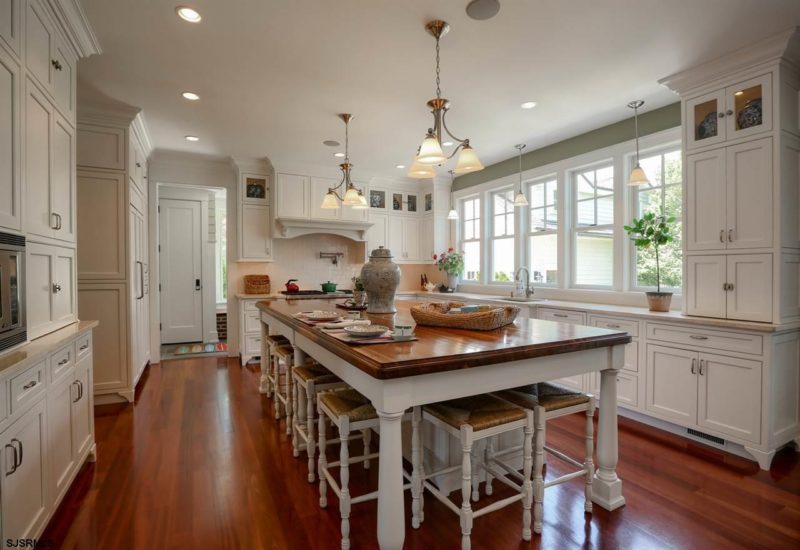 A kitchen with a wood floor and long island with barstools