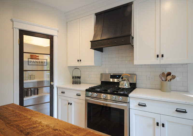 Stove with vent hood in kitchen and door to pantry