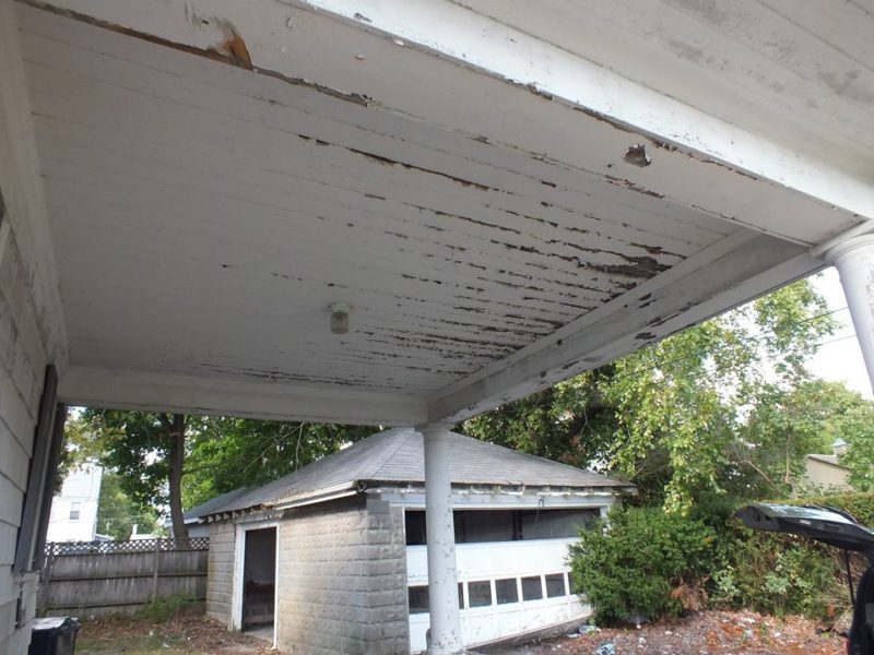 Closeup of paint peeling on ceiling of porch covering