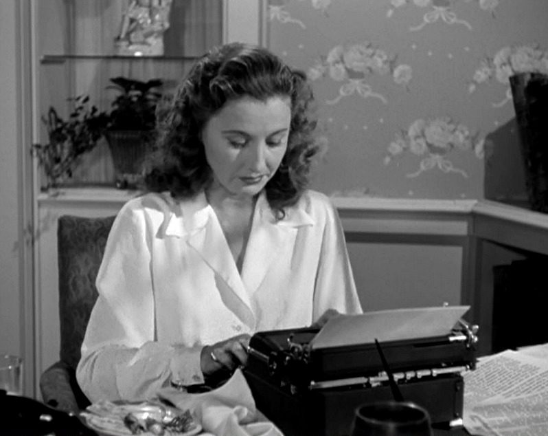 Barbara Stanwyck typing on a typewriter