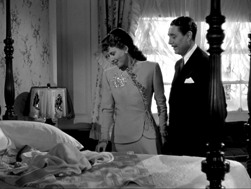 Roberta the baby lying on the four poster bed while Elizabeth and John look on