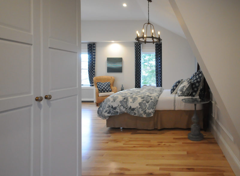 Owner\'s bedroom after remodel with hardwood floor and chandelier