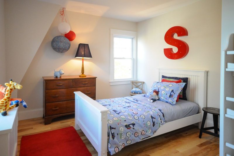 A boy\'s bedroom with large red letter S hanging above headboard of bed