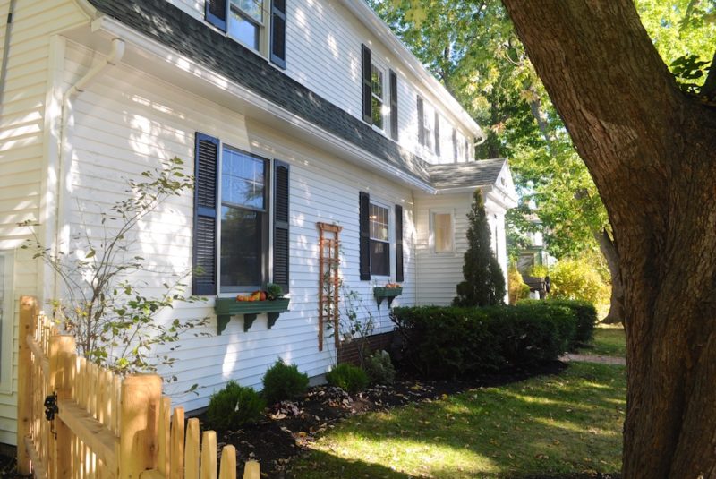 Front exterior view of white Colonial-style house with black shutters