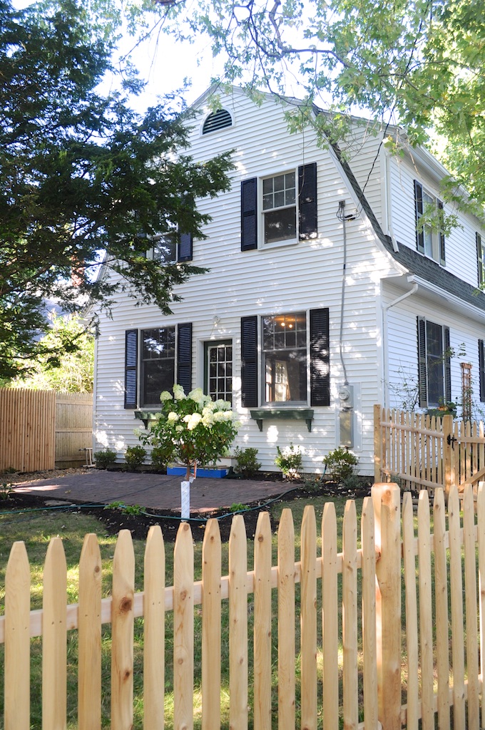 Side exterior view of house after remodel with new picket fence