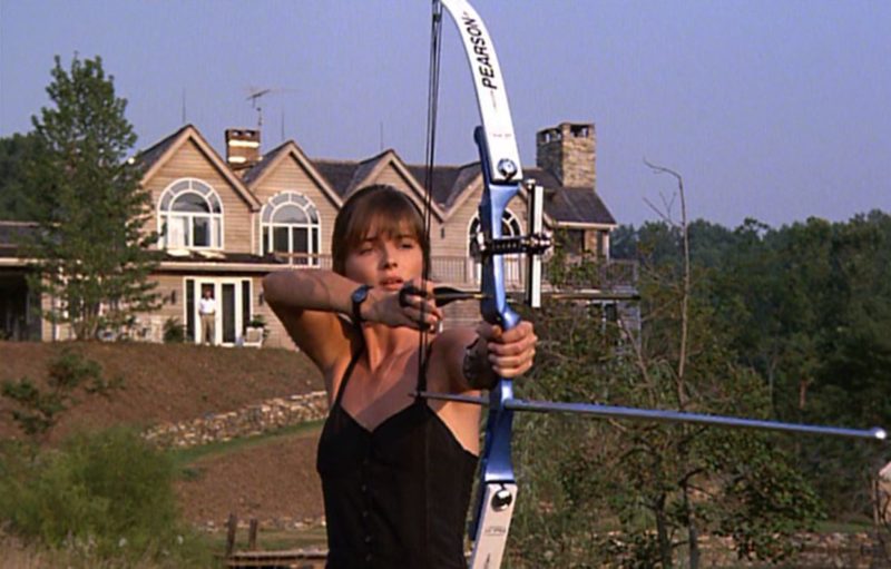 Paulina shooting an arrow in front of house