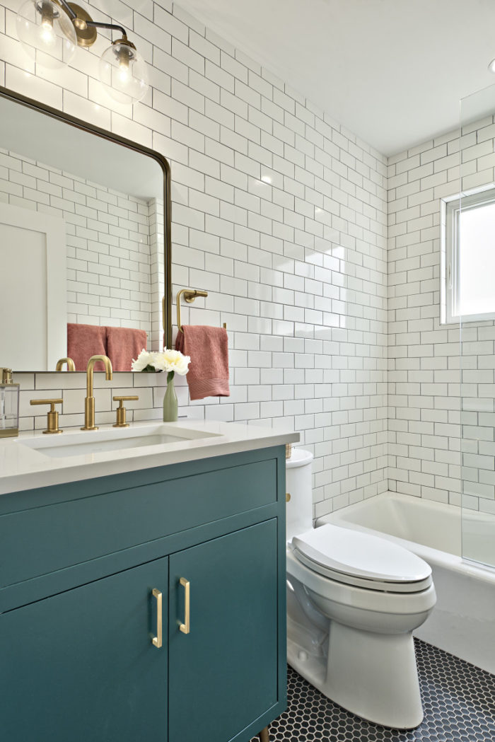 Bathroom with teal vanity and brass faucet