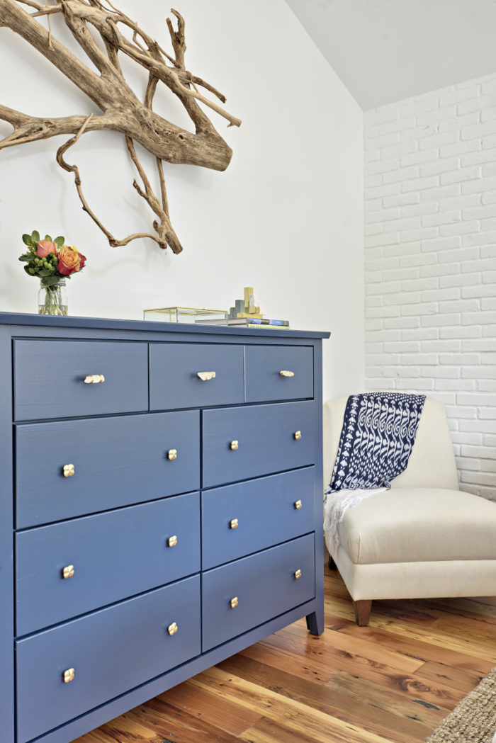 Blue bedroom dresser and white chair with throw