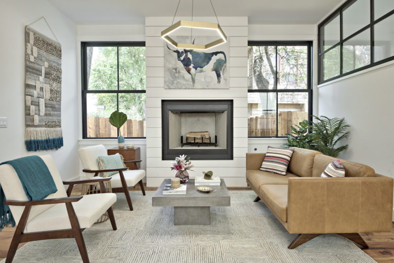 A living room filled with furniture, shiplap walls and large windows