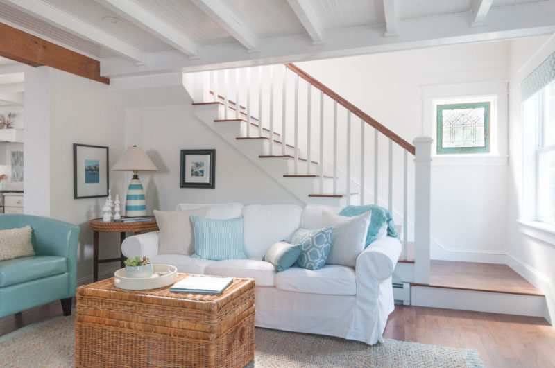 A living room with staircase and white slipcovered sofa