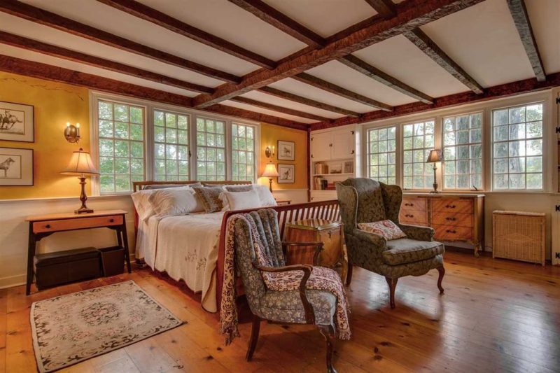 Bedroom with beamed ceiling, bed, and two chairs